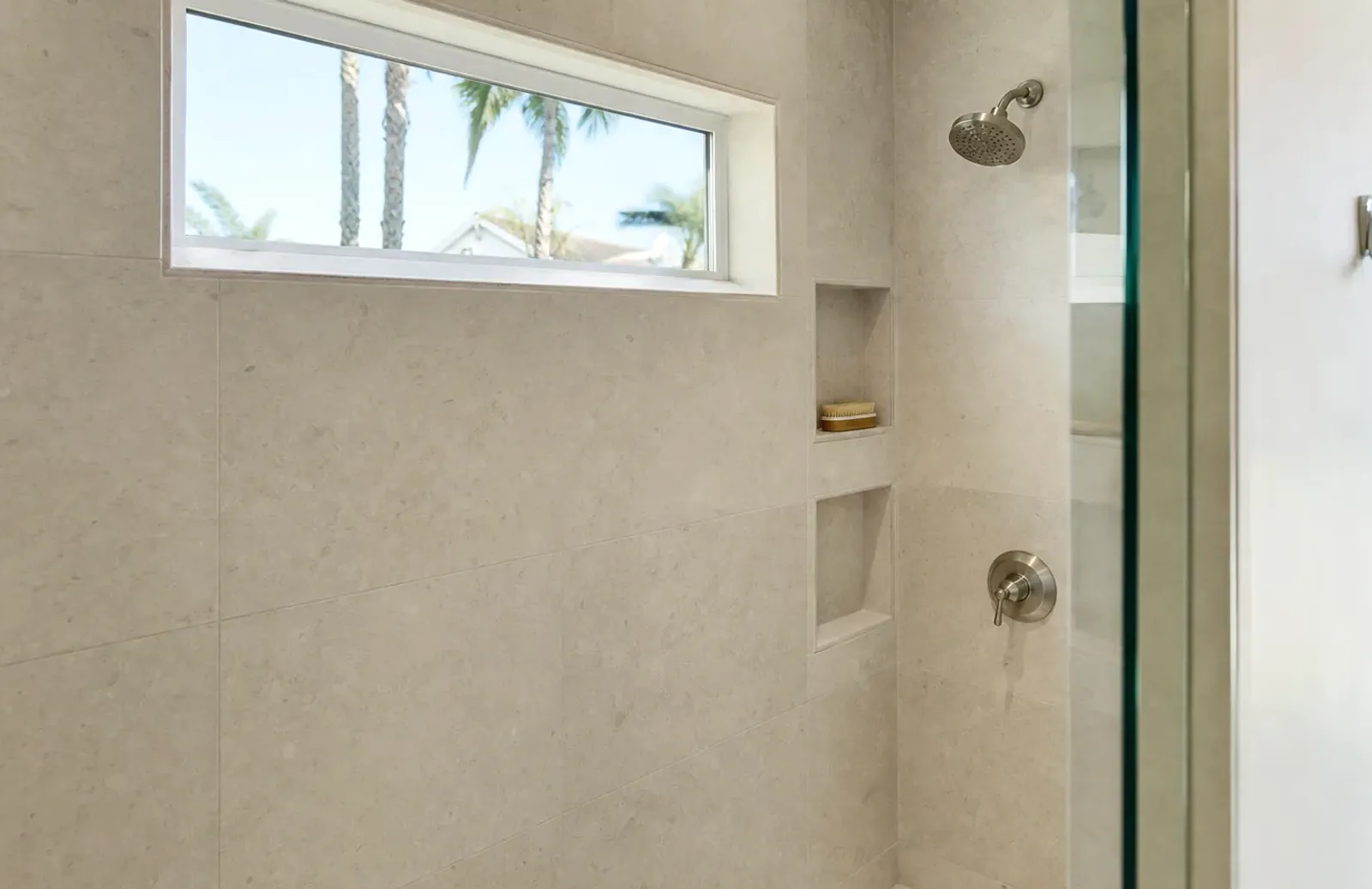 Tiled shower with a high window and a recessed niche